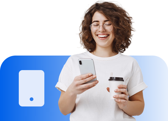 Mulher sorridente com cabelo cacheado segurando um celular na mão direita e um copo descartável na mão esquerda.